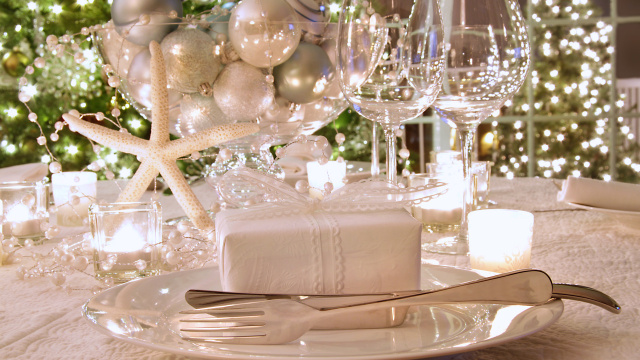 Elegantly lit  holiday dinner table with white ribbon gift