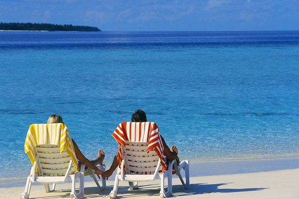 Couple Holding Hands on Beach Chairs