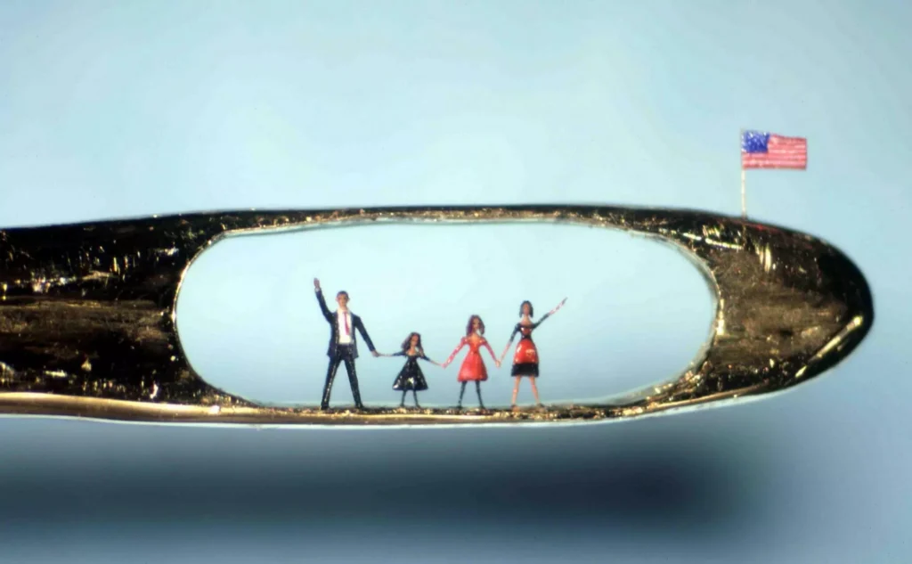 Micro-sculpture by Willard Wigan of Barack Obama and his family inside the eye of a needle, accompanied by a tiny American flag.