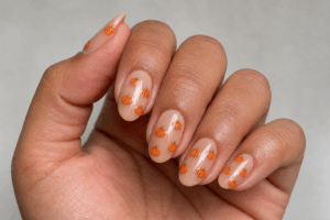 Set of manicured nails with clear base coat and pumpkin designs
