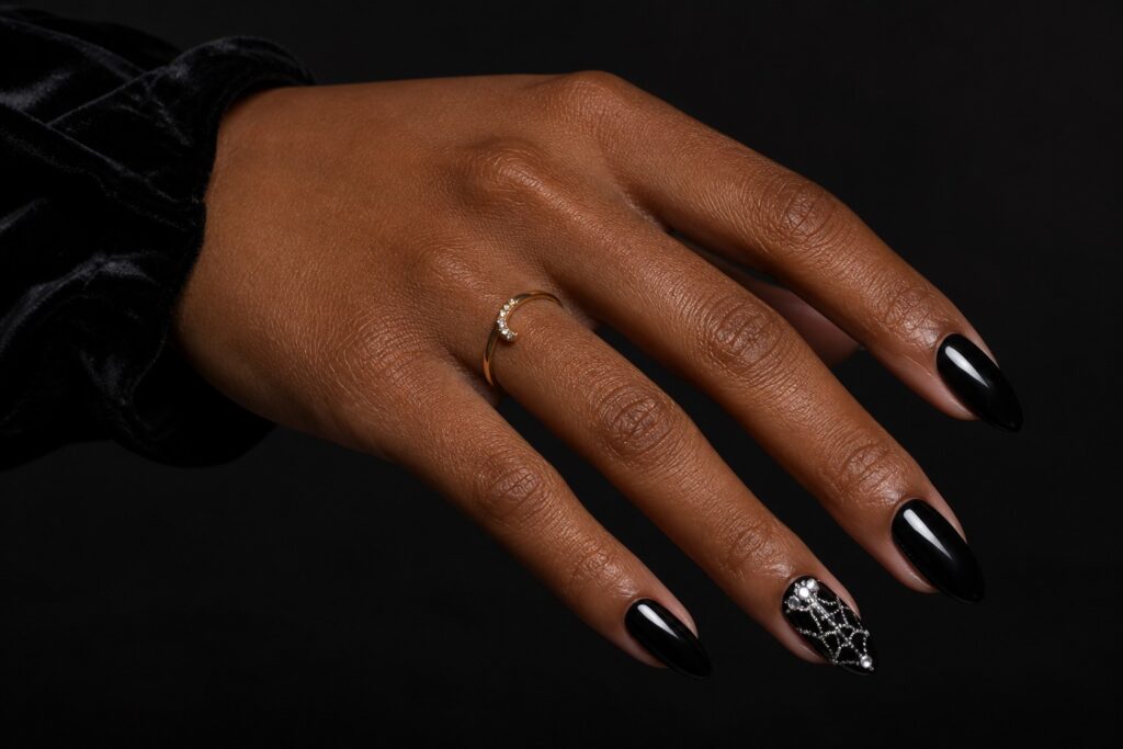 Glossy black almond nails with a rhinestone spiderweb accent nail